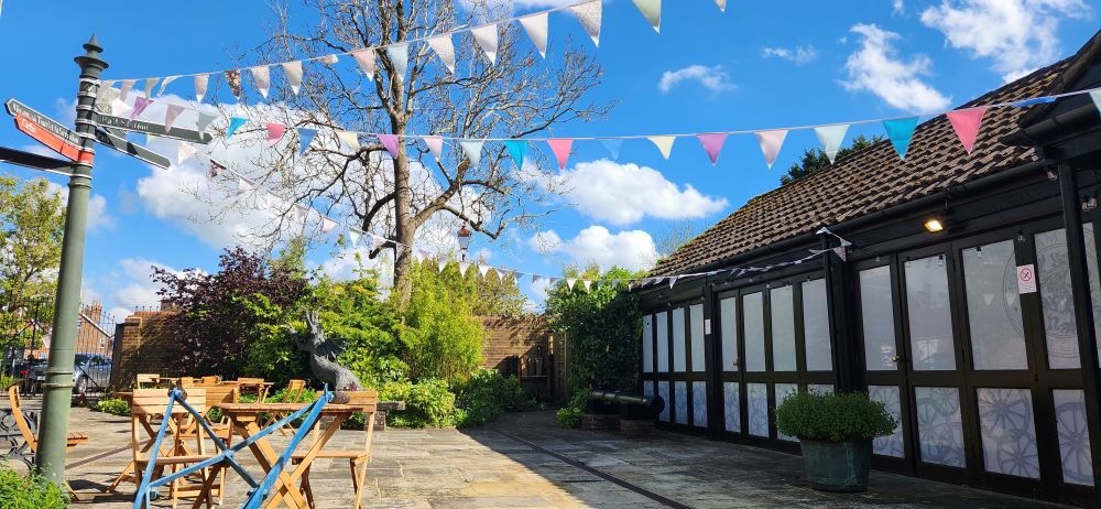 Image taken in Horsham Museum's garden on a sunny day. Bunting and chairs and tables can be seen in the foreground.