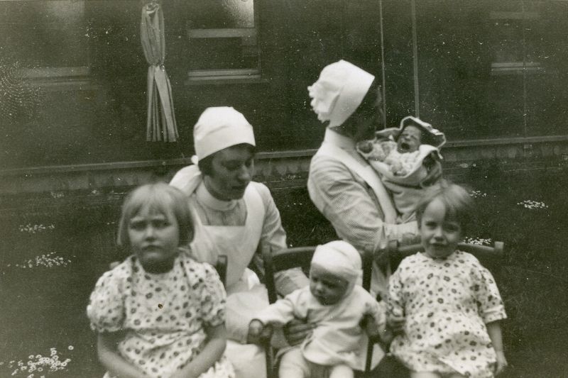 Two nurses pictured in uniform with four young children