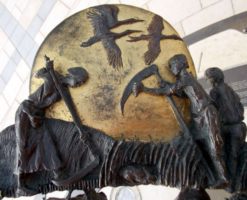 Photograph of part of the Horsham sundial showing people harvesting grain.