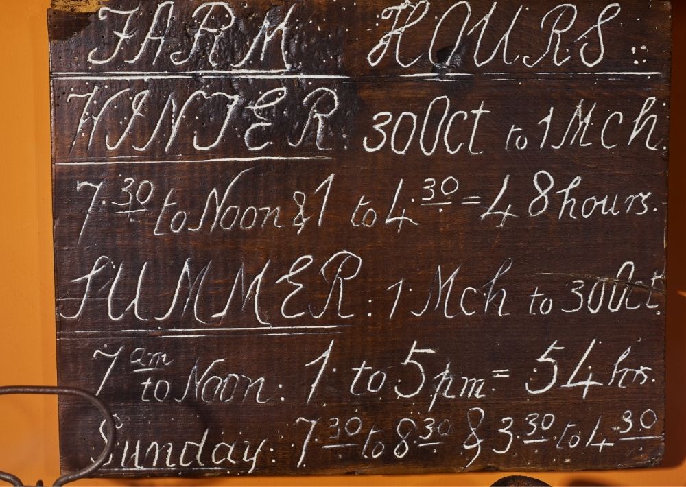 Wooden board inscribed with the opening hours of a farm.