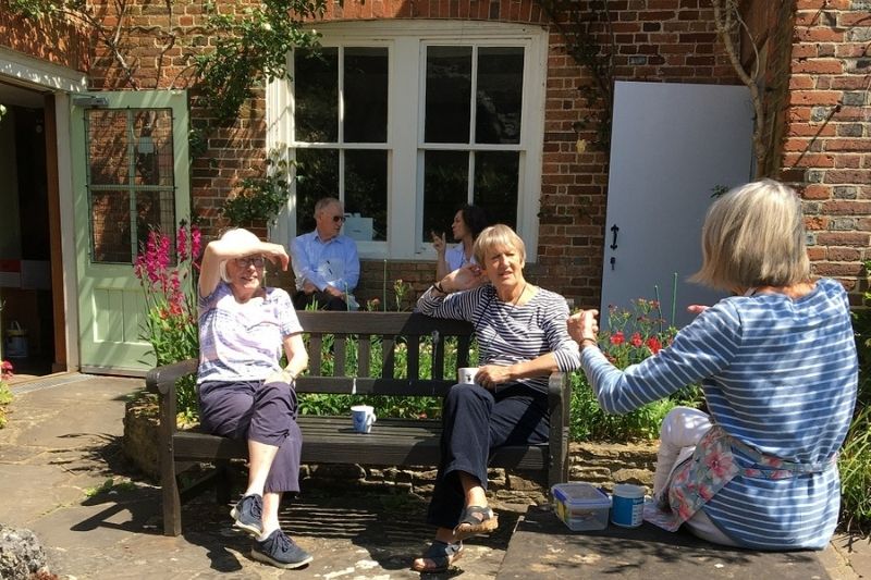 The museum team take a break on benches in the sunny garden