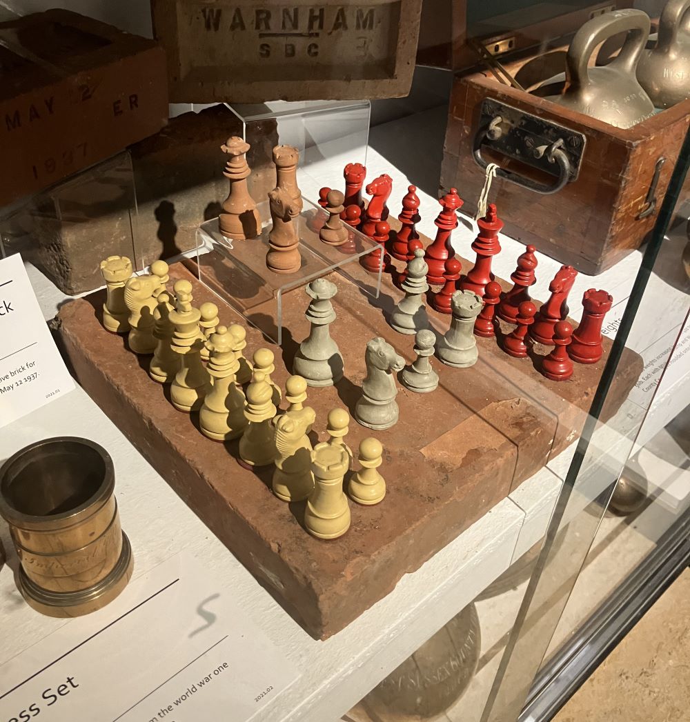 Carved set of wooden chess pieces in a display case.