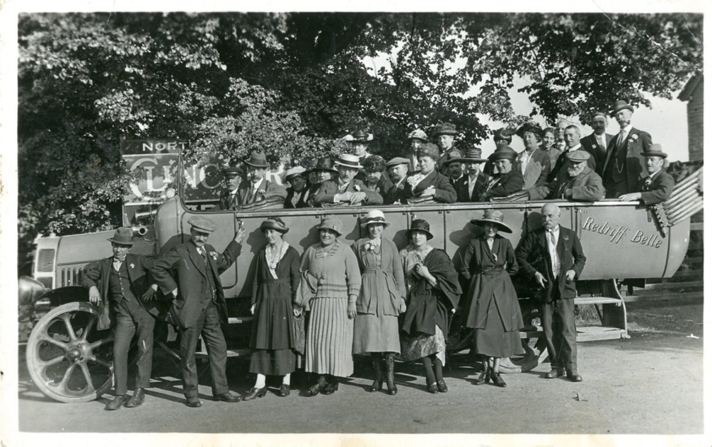 A black and white photo of an outing in an old-fashioned motor coach