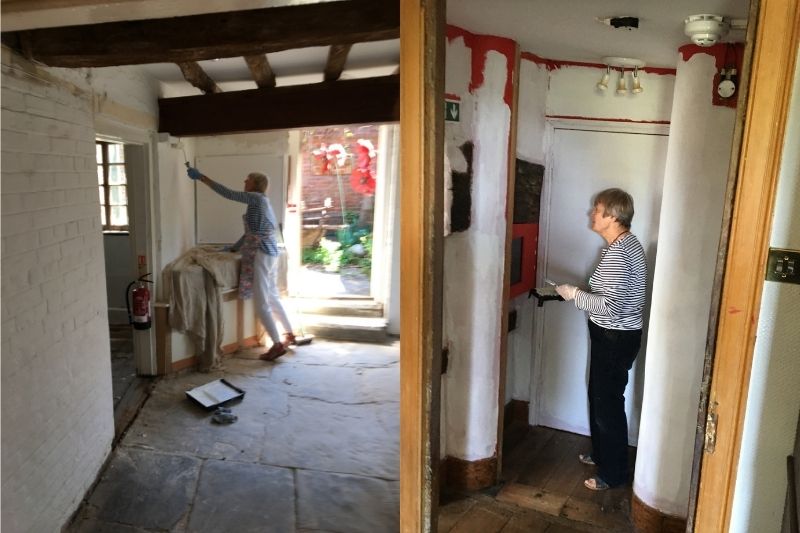 Two volunteers paint a white undercoat over the museum's existing bright colours