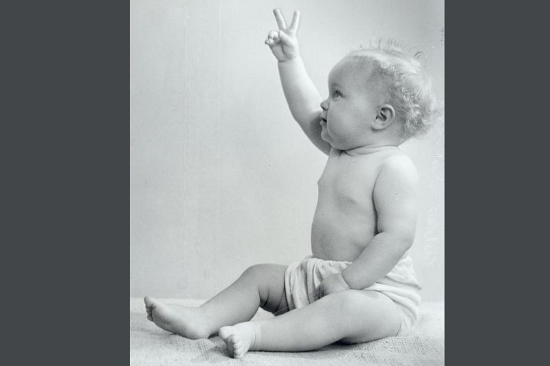 Baby with two fingers up in the air for victory