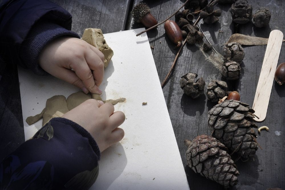 A child with a pencil and paper and pine cones